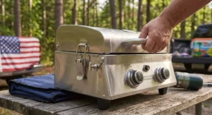 Portable tabletop gas grill locked shut and held by its integrated carrying handle for tailgating