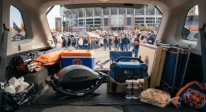 Collapsible portable grill folded neatly into a car trunk with other tailgating accessories