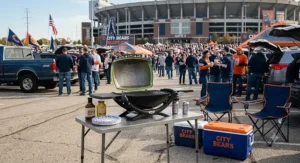 Lightweight tabletop portable grill displayed alongside tailgating coolers and lawn chairs